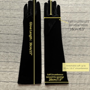 May include: A pair of black velvet opera gloves with a total length of 15 inches. The middle finger measures 3.5 inches, the palm circumference is 6.3 inches, the cuff circumference is 7.9 inches, and the cuff stretches up to 10.2 inches.