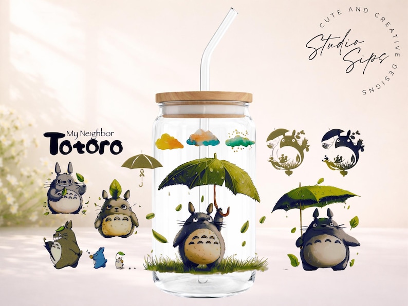 May include: A clear glass tumbler with a wooden lid and a glass straw. The tumbler is decorated with illustrations of characters from "My Neighbor Totoro," including Totoro holding an umbrella. The words "Cute and Creative Designs" are also visible.