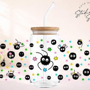 May include: Clear glass tumbler with a wooden lid and a glass straw. The tumbler is decorated with black soot sprites and colorful stars. The text "CUTE AND CREATIVE DESIGNS Studio Sips" is visible on the top right.