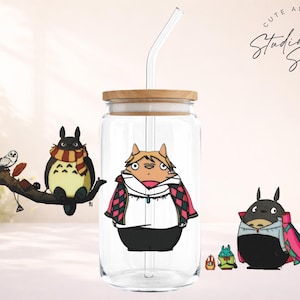 May include: A clear glass tumbler with a wooden lid and a straw, featuring cartoon illustrations of characters. The tumbler has a design of a character in a white shirt and black pants. Other characters are also present.