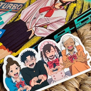 May include: A colorful sticker featuring four anime-style characters making heart shapes with their hands. The characters are wearing various outfits, including school uniforms and maid attire. The background includes a manga illustration and the word "TURBO".