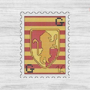 May include: A cross-stitch design of a postage stamp featuring a gold lion emblem on a red and yellow striped background. The stamp has a perforated edge and the letters "G" and "A" are visible. A PDF icon is in the upper right corner.