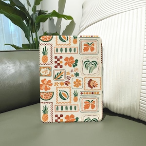 Puede incluir: Una funda beige para tableta con un patrón repetido de frutas y flores tropicales en naranja, verde y marrón. El diseño incluye piñas, flores de hibisco y otros elementos botánicos dentro de marcos decorativos. La funda es rectangular con esquinas redondeadas.