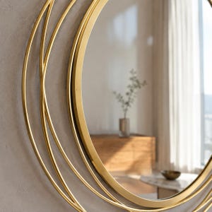 Peut inclure: Un miroir mural circulaire dot&eacute; d'un cadre en m&eacute;tal dor&eacute; poli. Le cadre est compos&eacute; de plusieurs anneaux fins, concentriques et superpos&eacute;s, cr&eacute;ant un effet g&eacute;om&eacute;trique en couches autour de la surface centrale en verre r&eacute;fl&eacute;chissant.