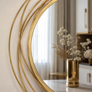 Peut inclure: Un miroir mural circulaire dot&eacute; d'un cadre d&eacute;coratif compos&eacute; de plusieurs anneaux m&eacute;talliques dor&eacute;s fins et superpos&eacute;s. Le cadre pr&eacute;sente une finition m&eacute;tallique polie et la surface du miroir refl&egrave;te un int&eacute;rieur avec un vase dor&eacute; et des fleurs.