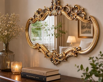 Peut inclure: Un miroir mural doré orné doté d'un cadre décoratif incurvé avec des volutes complexes et une crête centrale. Le miroir reflète une pièce avec une fenêtre, une lampe et un tableau encadré, tandis que le cadre présente une finition métallique polie.