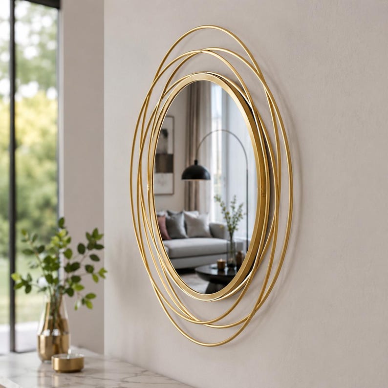 Peut inclure: Un miroir mural ovale dot&eacute; d'un cadre en m&eacute;tal dor&eacute; compos&eacute; de plusieurs anneaux concentriques superpos&eacute;s. La surface en verre r&eacute;fl&eacute;chissant est centr&eacute;e dans la structure circulaire, cr&eacute;ant un aspect g&eacute;om&eacute;trique superpos&eacute; au mur.