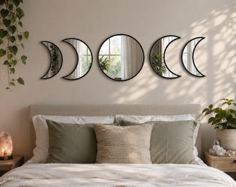 Peut inclure: Un ensemble de cinq miroirs muraux avec des cadres noirs disposés en ligne horizontale. La collection comprend un grand miroir circulaire au centre, flanqué de deux paires de miroirs en forme de croissant de lune de tailles variées.