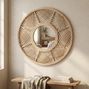 May include: A round, natural-toned rattan mirror with a woven design. The mirror has a circular center and is mounted on a light-colored wall. The mirror is above a wooden bench with a blanket and books.