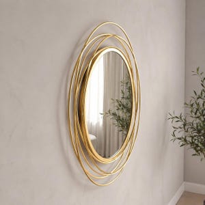 Peut inclure: Un miroir mural circulaire dot&eacute; d'un cadre dor&eacute; compos&eacute; de plusieurs anneaux m&eacute;talliques fins superpos&eacute;s. La surface en verre r&eacute;fl&eacute;chissant est centr&eacute;e dans le cadre, cr&eacute;ant un design concentrique en couches qui s'&eacute;tend vers l'ext&eacute;rieur.