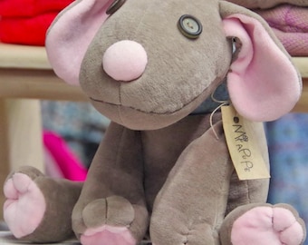 May include: A gray plush dog toy with pink ears and paws. The dog has a button nose and button eyes. The toy has a tag that says "Mia & Pe."