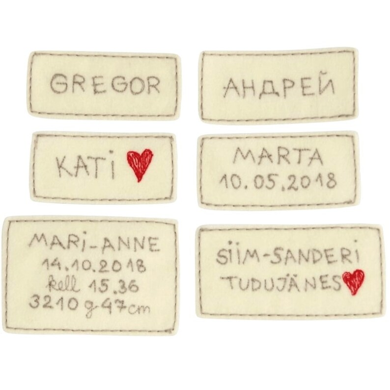 Puede incluir: Seis etiquetas de fieltro beige con texto bordado y corazones rojos. Las etiquetas dicen "Gregor", "Андрей", "Kati", "Marta 10.05.2018", "Mari-Anne 14.10.2018 kell 15.36 3210 g 47 cm" y "Siim-Sanderi Tudujanes".