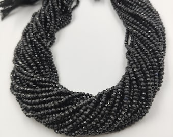 May include: A black beaded necklace with multiple strands. The beads are small and faceted, creating a sparkling effect. The necklace has a tassel at the top. The beads are strung together to form a necklace.