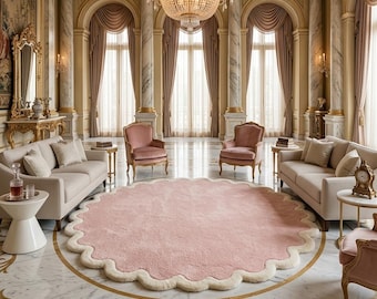May include: A large, round, light pink area rug with a thick, cream-colored scalloped border. The rug is placed on a polished white marble floor with gold inlay patterns, centered in a room with two beige sofas and two pink armchairs.