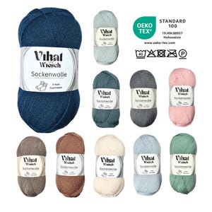 Può includere: Una collezione di gomitoli di filato colorati in varie tonalità, tra cui blu, grigio, rosa e verde. Ogni gomitolo ha un'etichetta con il testo "Vihat Wiesch Sockenwolle" e "4-fach Superwash". L'immagine include anche il logo Oeko-Tex Standard 100.