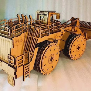Op de afbeelding: Een houten model van een Caterpillar 994 wiellader. Het model is gemaakt van lichtbruin hout en heeft ingewikkelde details, waaronder ladders, relingen en grote wielen. Het nummer "994" is zichtbaar aan de zijkant.