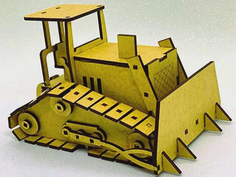 Op de afbeelding: Een geel houten bulldozer model met donkerbruine randen. De speelgoedbulldozer heeft een blad, rupsbanden en een cabine met een dak. Het model is gemaakt van uitgesneden houten stukken en in elkaar gezet om een 3D-effect te cre&euml;ren.