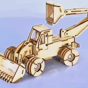 Op de afbeelding: Een houten model van een bouwmachine, met een voorste bak en een gelede arm met een tweede bak. Het model heeft gedetailleerde wielen en een cabine. Het voertuig is gemaakt van lichtgekleurd hout.