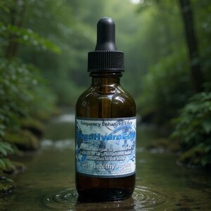 May include: A brown glass bottle with a black dropper, labeled "MegaHydroCure." The label includes the text "Frequency Enhanced Elixir" and "Get Healthy Again." The bottle is set against a blurred natural background of a stream.