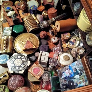 May include: A collection of antique and vintage items, including small boxes, trinkets, and decorative objects. The items are in various shapes, sizes, and colors, with materials like wood, metal, and glass. A variety of textures and patterns are visible.