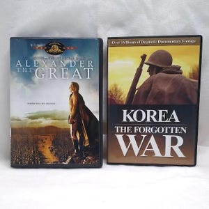 May include: Two DVD cases. The left case is for "Alexander the Great" with a movie poster image. The right case is for "Korea: The Forgotten War" with a soldier image and text "Over 16 Hours of Dramatic Documentary Footage."