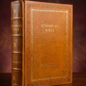 Può includere: Una Bibbia etiope rilegata in pelle marrone con scritte dorate e un bordo decorativo. Il dorso e la copertina sono di un caldo colore marrone. Il libro è esposto in posizione verticale su una superficie di legno.