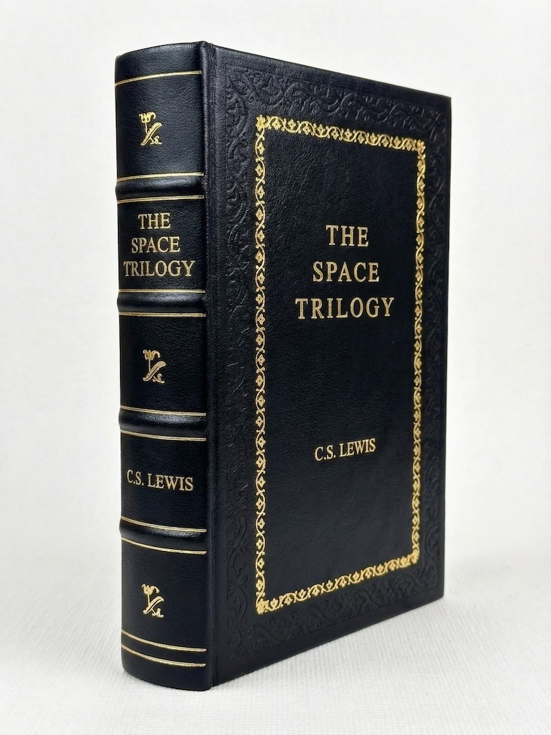 May include: A black hardcover book titled "The Space Trilogy" by C.S. Lewis, with gold lettering and decorative borders. The spine also features gold lettering and embellishments. A classic trilogy.