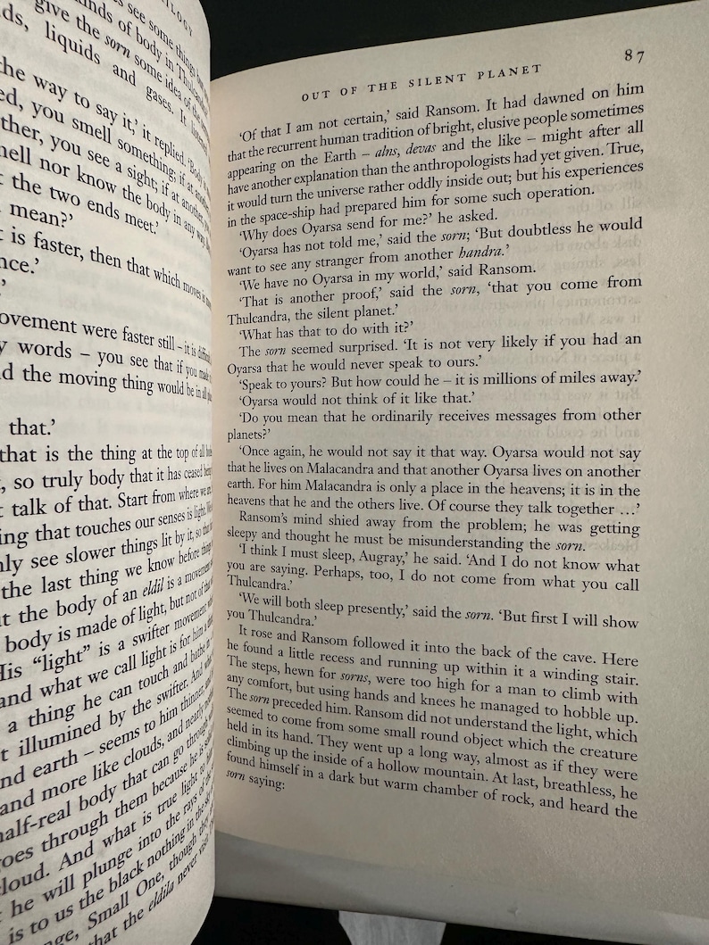 May include: An open book displaying text from C.S. Lewis's "Out of the Silent Planet". The pages are aged, with black text. The book is open to a page with the number 87 in the top right corner.