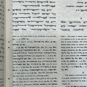 May include: Open book with text in an ancient script. The pages are yellowed, and the text is in black ink. The book is open to a page with multiple lines of text, with some numbers and abbreviations.