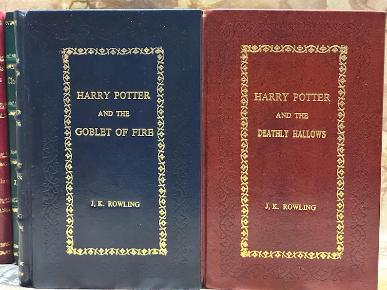 May include: Two hardback books from the Harry Potter series. The first book is dark blue with gold lettering and the title "Harry Potter and the Goblet of Fire" by J.K. Rowling. The second book is burgundy with gold lettering and the title "Harry Potter and the Deathly Hallows".