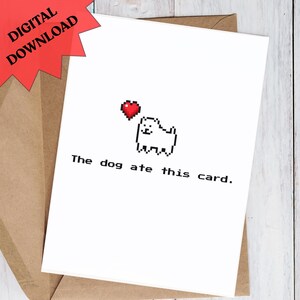 Könnte beinhalten: Weiße Grußkarte mit einem pixeligen Hund und einem roten Herz. Der Text "The dog ate this card" steht darunter. Ein roter "DIGITAL DOWNLOAD" Aufkleber befindet sich oben links. Die Karte liegt in einem braunen Umschlag.