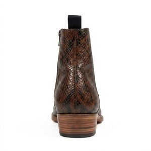 May include: Brown and black ankle boot with a snakeskin pattern. The boot has a side zipper, a pull tab, and a stacked wooden heel. The boot is made of leather and has a pointed toe.