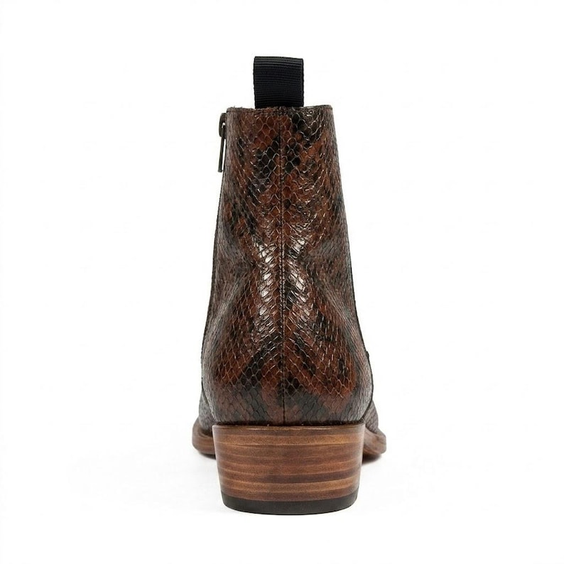 May include: Brown and black ankle boot with a snakeskin pattern. The boot has a side zipper, a pull tab, and a stacked wooden heel. The boot is made of leather and has a pointed toe.