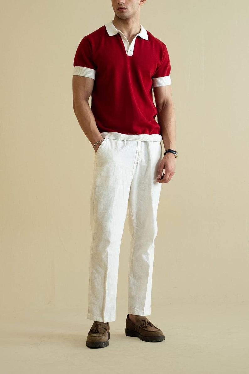 Op de afbeelding: Een persoon draagt een rood poloshirt met witte kraag en manchetten, gecombineerd met een witte linnen broek en bruine schoenen. De outfit is een klassieke, casual stijl.