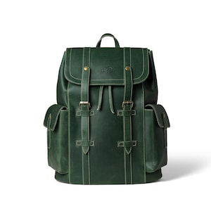 Può includere: Zaino in pelle verde con due tasche laterali e una patta superiore fissata da cinghie e fibbie. Lo zaino ha una maniglia superiore e una chiusura con coulisse. Le cuciture sono di colore verde chiaro. Lo zaino ha un logo sulla patta superiore.