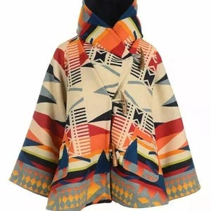 May include: A colorful poncho-style coat with a geometric pattern in shades of cream, red, orange, blue, and gray. The coat features a high collar, toggle closures, and wide sleeves. The design includes triangles, stripes, and diamond shapes.
