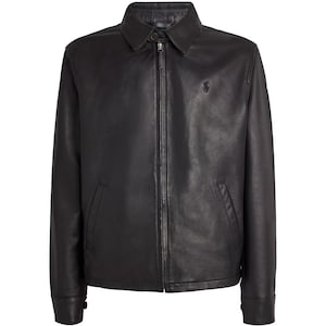 Op de afbeelding: Zwarte leren jas met een kraag, een ritssluiting aan de voorkant en twee zijzakken. De jas heeft lange mouwen met manchetten met knopen en een klein logo op de borst.