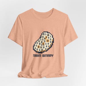 May include: A peach-coloured t-shirt with a pixelated naan bread design filled with binary code. The text "NAAN BINARY" is below the naan graphic in a bold, sans-serif font. The shirt has short sleeves and a crew neck.