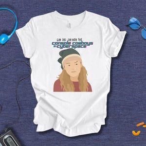 Może przedstawiać: Biała koszulka z grafiką kobiety w zielonym kapeluszu i napisem "CAN YOU JAM WITH THE CONSOLE COWBOYS in CYBERSPACE". Kobieta ma blond włosy i czerwoną koszulkę.