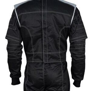 May include: Black racing suit with white stitching and gray accents on the shoulders and collar. The suit has long sleeves with black cuffs and is designed for motorsports. The back view shows the suit's construction and detailing.