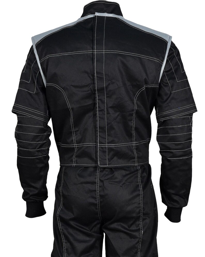 May include: Black racing suit with white stitching and gray accents on the shoulders and collar. The suit has long sleeves with black cuffs and is designed for motorsports. The back view shows the suit's construction and detailing.