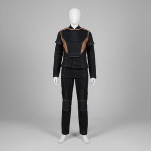 Puede incluir: Conjunto negro de dos piezas con detalles cobrizos y costuras blancas. La chaqueta tiene cuello alto y detalles en los hombros. Los pantalones tienen paneles reforzados en las rodillas. El conjunto se exhibe en un maniqu&iacute;.