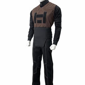 Puede incluir: Un atuendo completo que consta de un chaleco marr&oacute;n con un logotipo negro, una camisa negra de manga larga, pantalones negros con costuras blancas y un cintur&oacute;n negro. El atuendo se exhibe en un maniqu&iacute;.