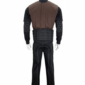 Puede incluir: Un disfraz completo exhibido en un maniqu&iacute;. El atuendo incluye pantalones negros con costuras blancas, una camisa negra de manga larga, un chaleco marr&oacute;n y un cintur&oacute;n negro. El chaleco y el cintur&oacute;n tienen costuras blancas.