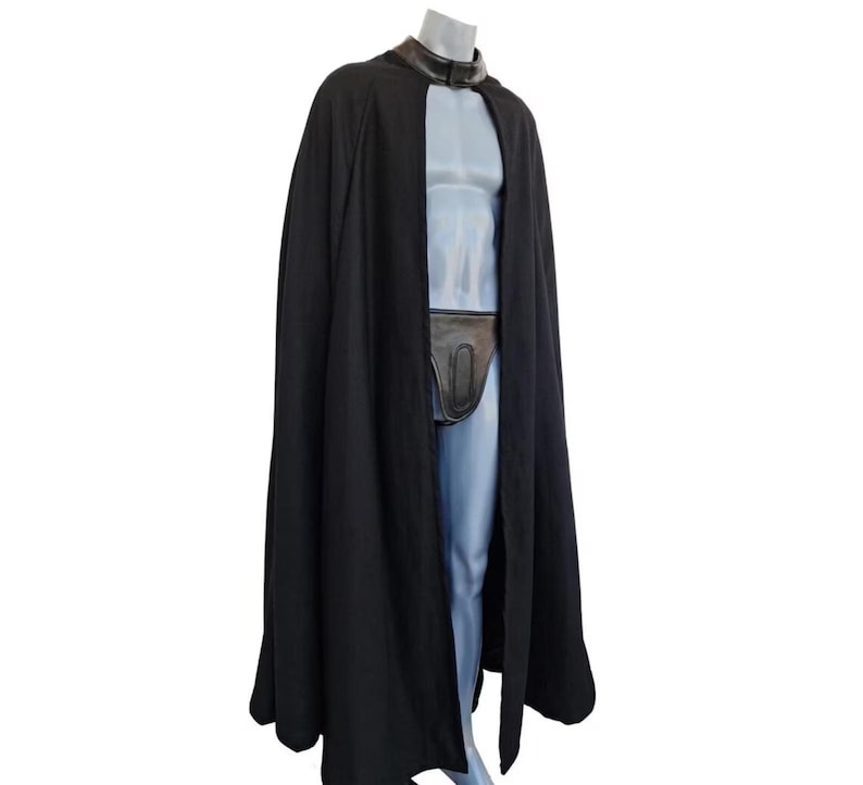 May include: A long, black cape with a leather collar and a matching leather pouch. The cape is draped over a mannequin, showcasing its flowing design. The outfit is a costume.