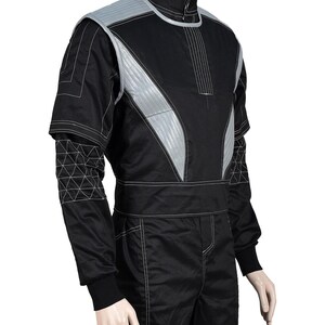 May include: Black racing suit with silver accents and white stitching. The suit features a high collar, quilted shoulder and chest panels, and geometric detailing on the sleeves. A black belt cinches the waist, and the suit appears to be made of a durable, possibly fire-resistant material.