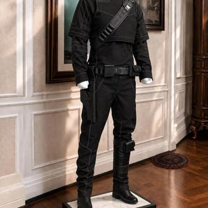 Pode incluir: Uma camisa preta de manga comprida com gola alta e costuras brancas em contraste, combinada com cal&ccedil;as pretas a condizer. O conjunto inclui um cinto utilit&aacute;rio preto com coldre, uma al&ccedil;a de ombro com bolsas e botas pretas com tiras.
