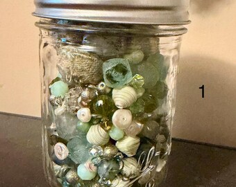 Pot Mason de 250 ml (1/2 pinte) contenant un assortiment de perles mystères, apprêts en verre, pierres précieuses et acrylique.