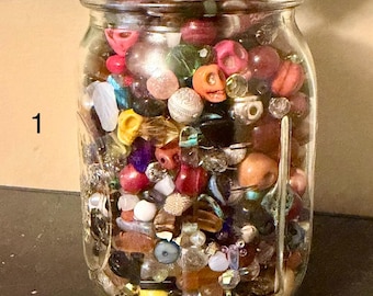 Pot Mason d'une pinte contenant un assortiment de perles mystères, apprêts en verre, pierres précieuses et acrylique.
