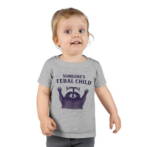 Funny “Someone’s Feral Child” Raccoon T-Shirt – Cute Wild Toddler Tee, Humorous Animal Shirt, Raccoon Graphic Tee for Kids or Adults